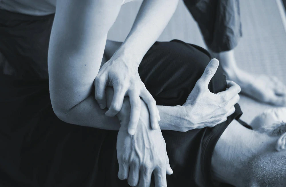 Therapeut strekt een arm van een cliënt in een shiatsubehandeling