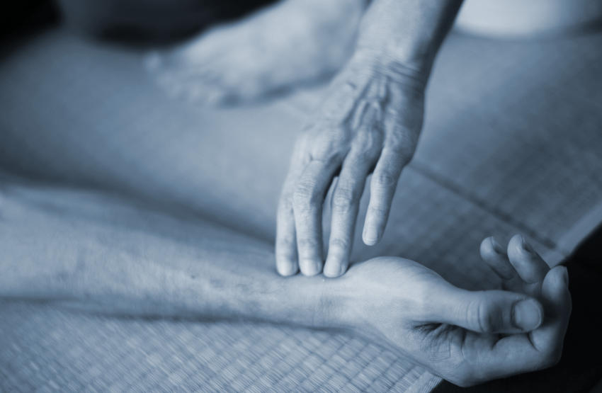 Hand with three finger tips on a client's wrist during a shiatsu treatment